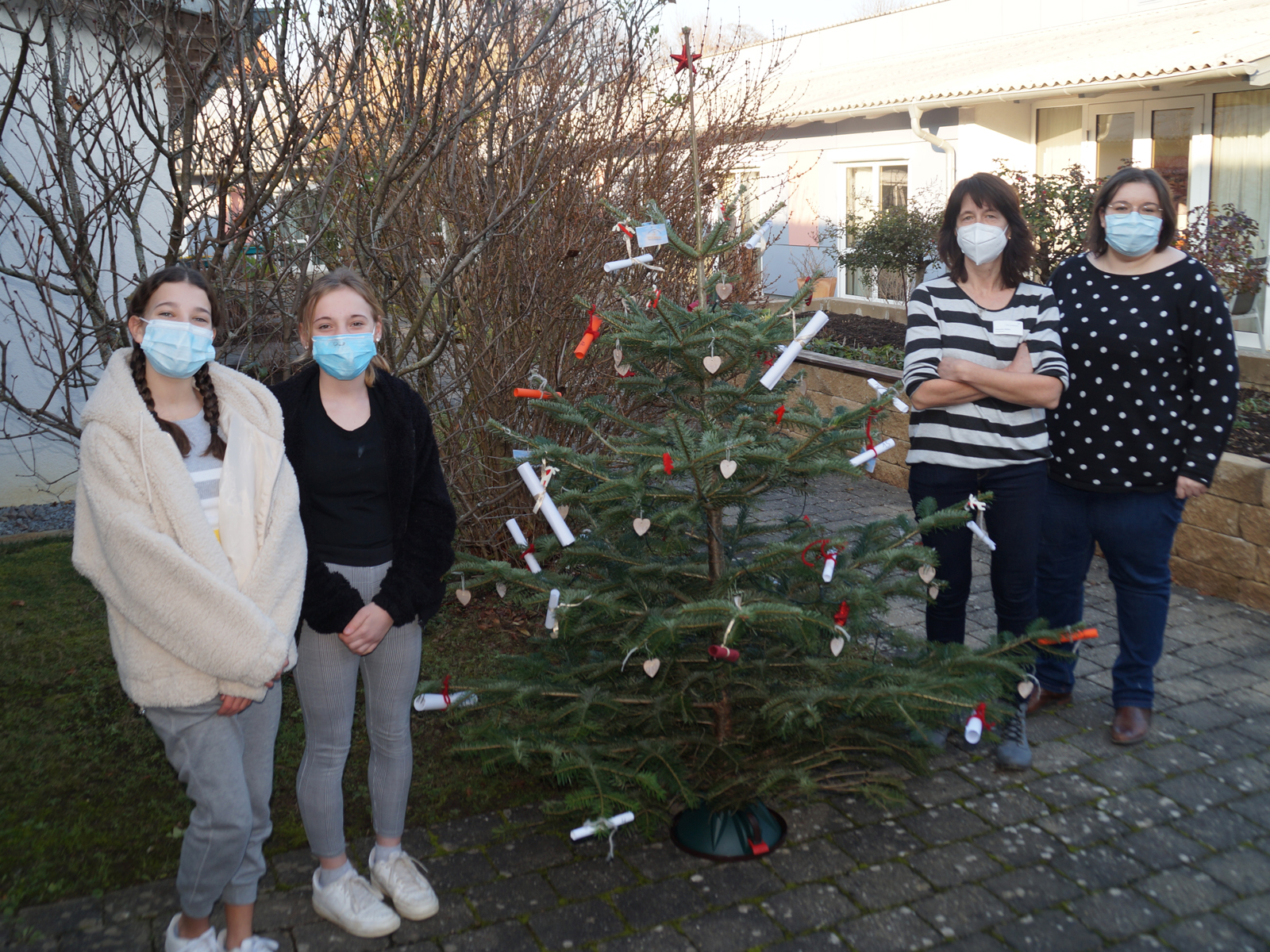  Zwei Schülerinnen der Lerngruppe 8 mit Einrichtungsleiterin Alexandra Waibel und Hauswirtschaftsleiterin Angelika Schöfer mit dem Baum an seinem zukünftigen Standort. 